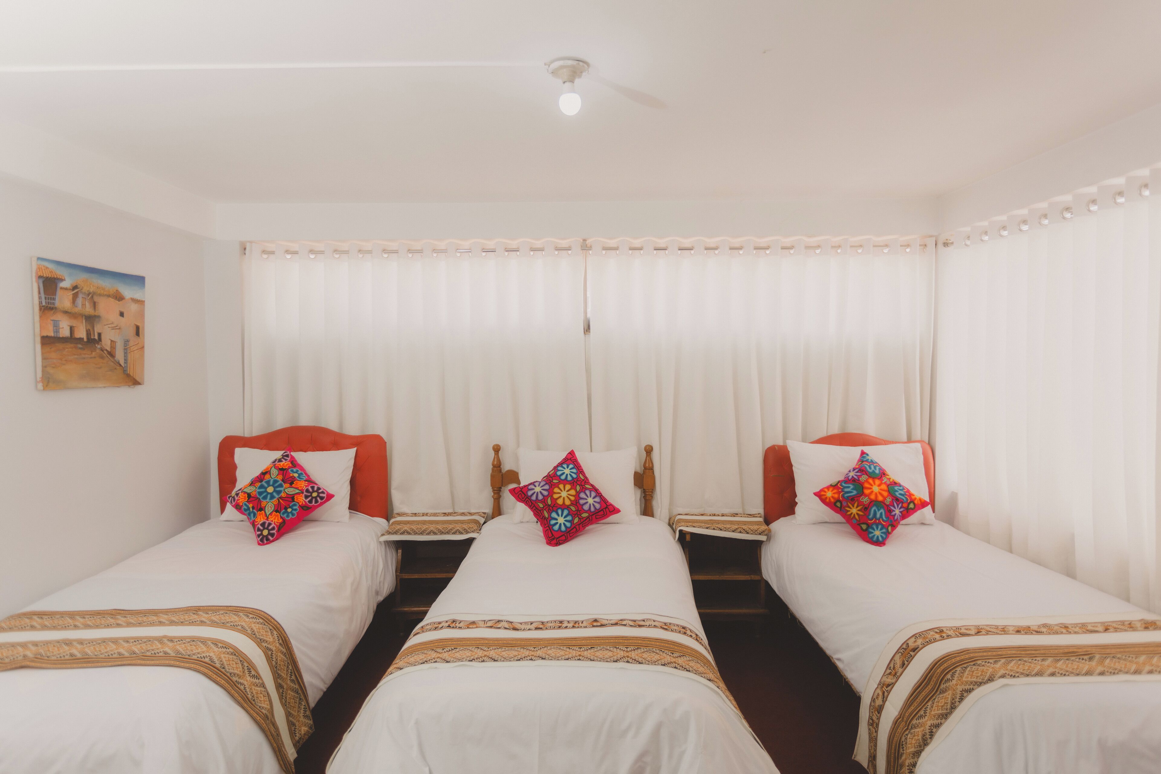 A hotel room with two single beds, white bedding, and colorful pillows.