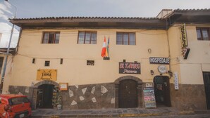 A building with a sign for 'JAMA RESTAURANT' and 'HOSPEDAGE PIZZERIA'. - Lucios Hostal (Cusco)