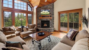 A spacious living room with a fireplace, large windows, and a cozy seating area.