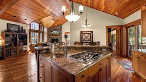 A spacious kitchen with a large island, wooden ceiling, and built-in cabinetry.