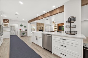 A modern kitchen with white cabinetry, a stainless steel dishwasher, and a wooden ceiling beam. - Whitewood Oasis-Your Poolside Retreat with  Heated  Pool in Spring, TX  (Spring)