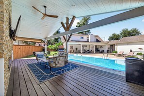 An outdoor pool area with a covered deck, lounge chairs, and a view of neighboring houses. - Whitewood Oasis-Your Poolside Retreat with  Heated  Pool in Spring, TX  (Spring)
