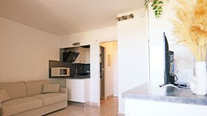 Een moderne woonkamer met een bank, een keukenhoek met een magnetron, en een eettafel.
