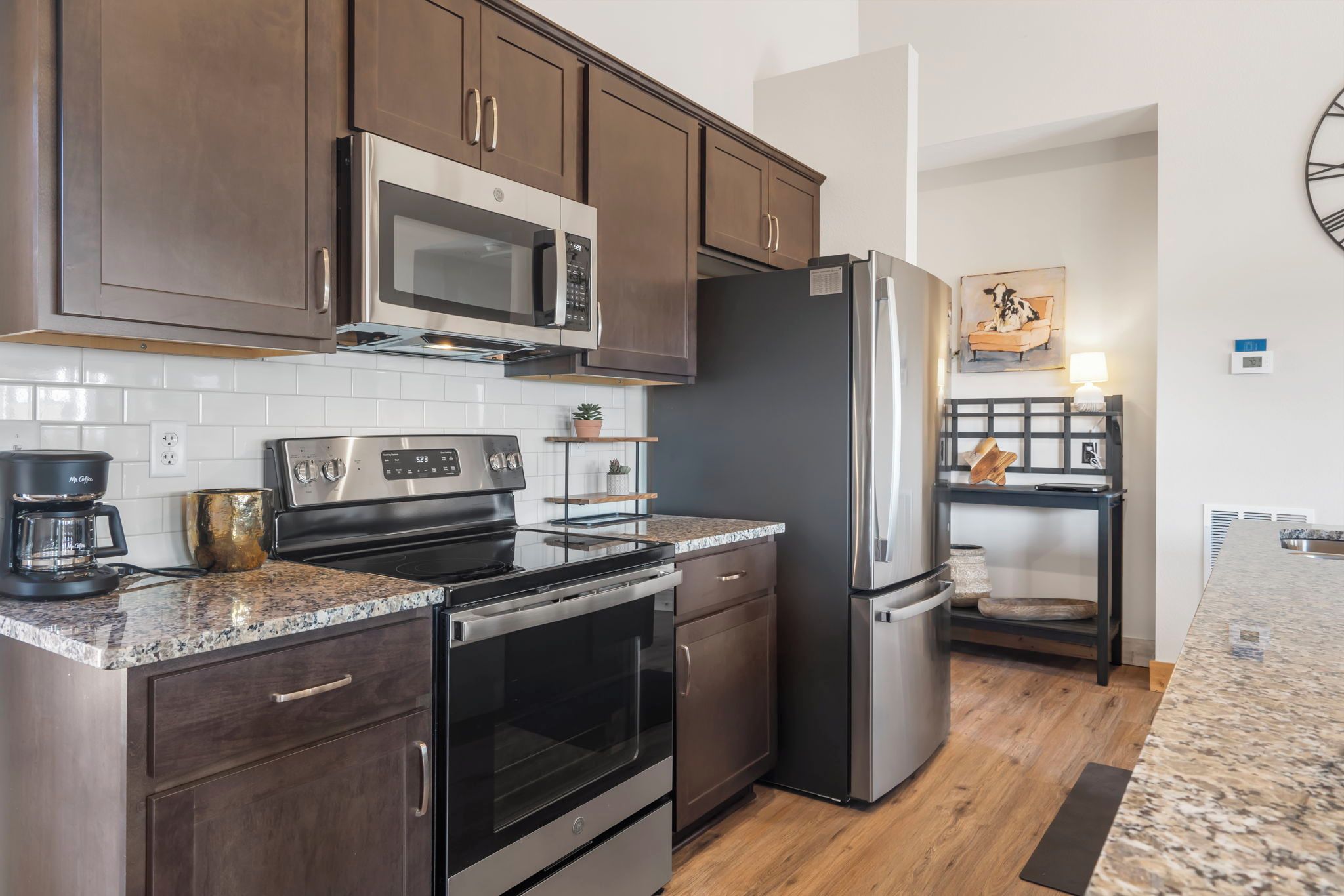 A modern kitchen with stainless steel appliances, dark wood cabinets, and a granite countertop.