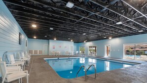 An indoor swimming pool with a blue floor, white lounge chairs, and a ceiling with exposed beams. - Lake Lookout Retreat with Private Hot Tub, Free Attraction Tickets & Community Pools (Branson)