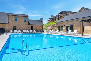 Une piscine avec des chaises longues et un bâtiment en bois doté d’un balcon.