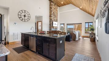 A spacious kitchen with a central island, a stone accent wall, and a large clock on the wall.