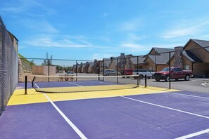 A tennis court with a net, surrounded by a fence, and vehicles parked nearby. - Lake Lookout Retreat with Private Hot Tub, Free Attraction Tickets & Community Pools (Branson)