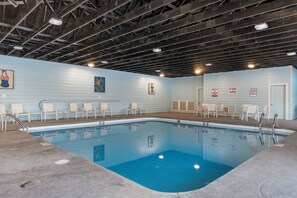 An indoor swimming pool with a blue floor, surrounded by white chairs and a lifeguard station. - Lake Lookout Retreat with Private Hot Tub, Free Attraction Tickets & Community Pools (Branson)