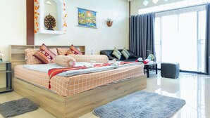 A modern bedroom with a large bed, a sofa, and a dining table. - Touch the Wind (Sap Yai)