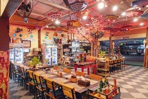 Un restaurante con piso a cuadros, mesas y sillas de madera, y diversas exhibiciones de comida y bebidas.
