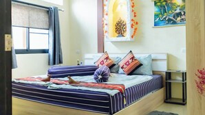 A bedroom with a bed, a nightstand, a lamp, a window with curtains, and a painting on the wall. - Touch the Wind (Sap Yai)
