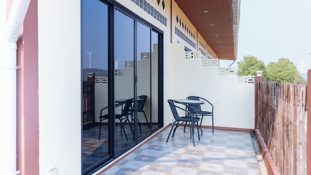A balcony with a tiled floor, a wooden fence, and two tables with chairs. - Touch the Wind (Sap Yai)