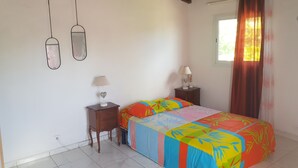 A bedroom with a bed, two bedside tables, a window with curtains, and a wooden ceiling. - Sunset inn (Sainte-Anne)