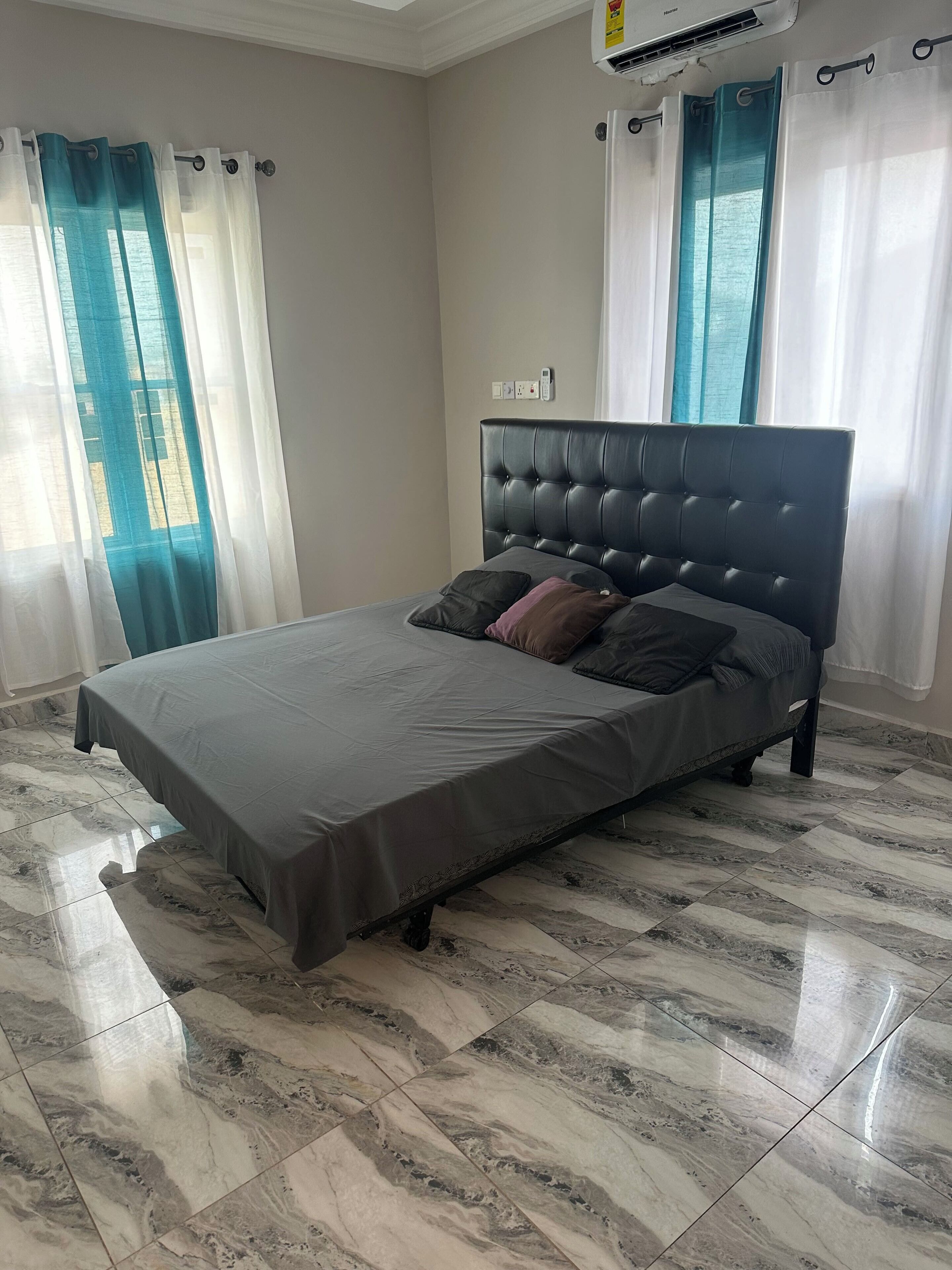 Une chambre à coucher avec un lit, un sol en marbre et des rideaux.