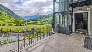 Un edificio moderno con grandes ventanales de vidrio que dan a un valle verde y montañas.