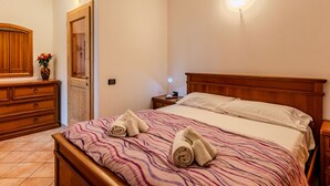 Un dormitorio con una cama de madera, una mesita de noche, un aparador y un espejo.