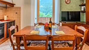Un comedor con mesa de madera, sillas y vistas a un bosque por una ventana.