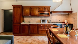 Una cocina con armarios de madera, salpicadero de azulejos, microondas, estufa y una mesa de comedor con sillas.