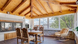A dining area with a wooden table and chairs, a stone wall, and large windows with a view of trees. - Villa Frane by Interhome (Maslenica)