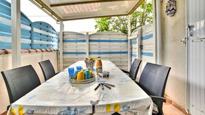 An outdoor patio with a covered table set for dining, surrounded by chairs. - Maisonneuve by Interhome (Ile d'Oléron)