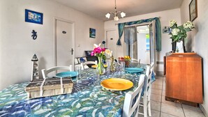 A dining area with a table set for four, a vase with flowers, and a decorative lighthouse. - Maisonneuve by Interhome (Ile d'Oléron)