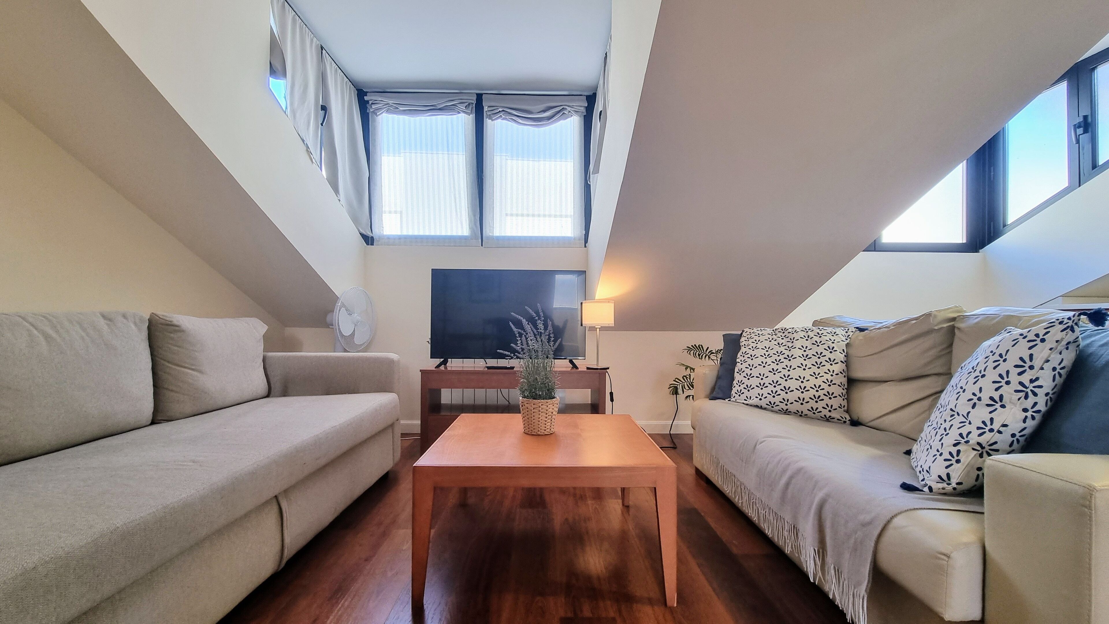 Ein modernes Wohnzimmer mit einer Couch, einem Couchtisch, einem Fernseher und einer Lampe.