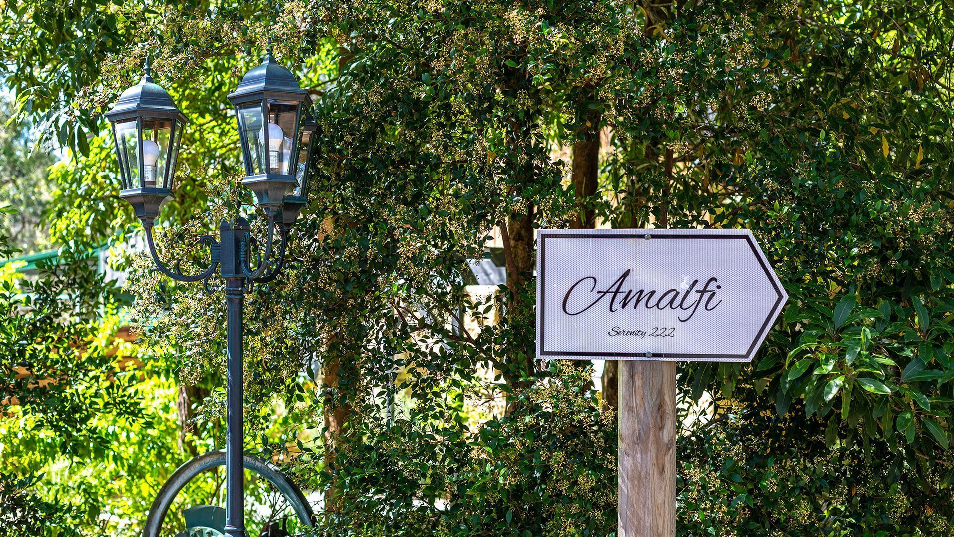 Une enseigne portant le nom « Amalfi » et l’adresse « Serenity 222 », le tout dans un cadre verdoyant et luxuriant.