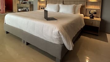 A modern hotel room with a large bed, a bedside table with a lamp, and a wooden headboard.