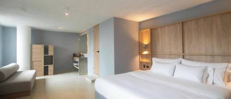 A modern hotel room with a large bed, a sofa, a wardrobe, and a desk.