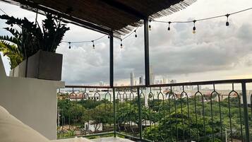 A balcony with a view of a cityscape, a railing, and string lights.