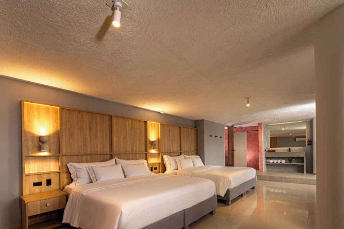 Quarto moderno com duas camas, cabeceiras de madeira e ilumina ção embutida.