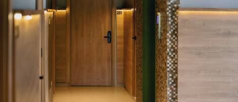 A hallway with wooden doors, a number 201 sign, and a patterned wall.