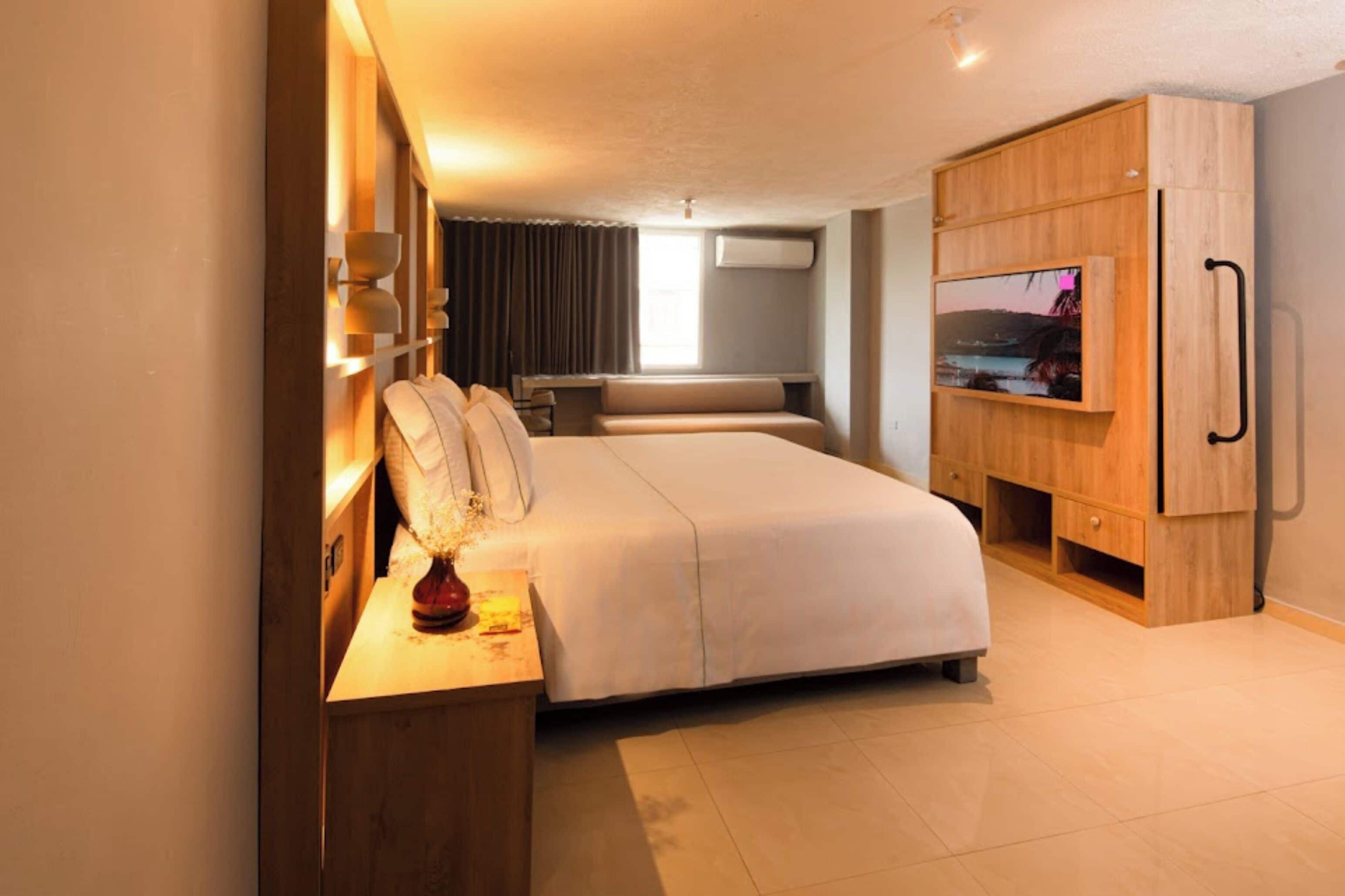 Una habitación de hotel moderna con una cama grande, un televisor y un armario de madera.