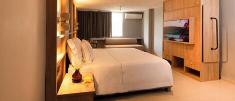 A modern hotel room with a large bed, a TV, and a wooden wardrobe.