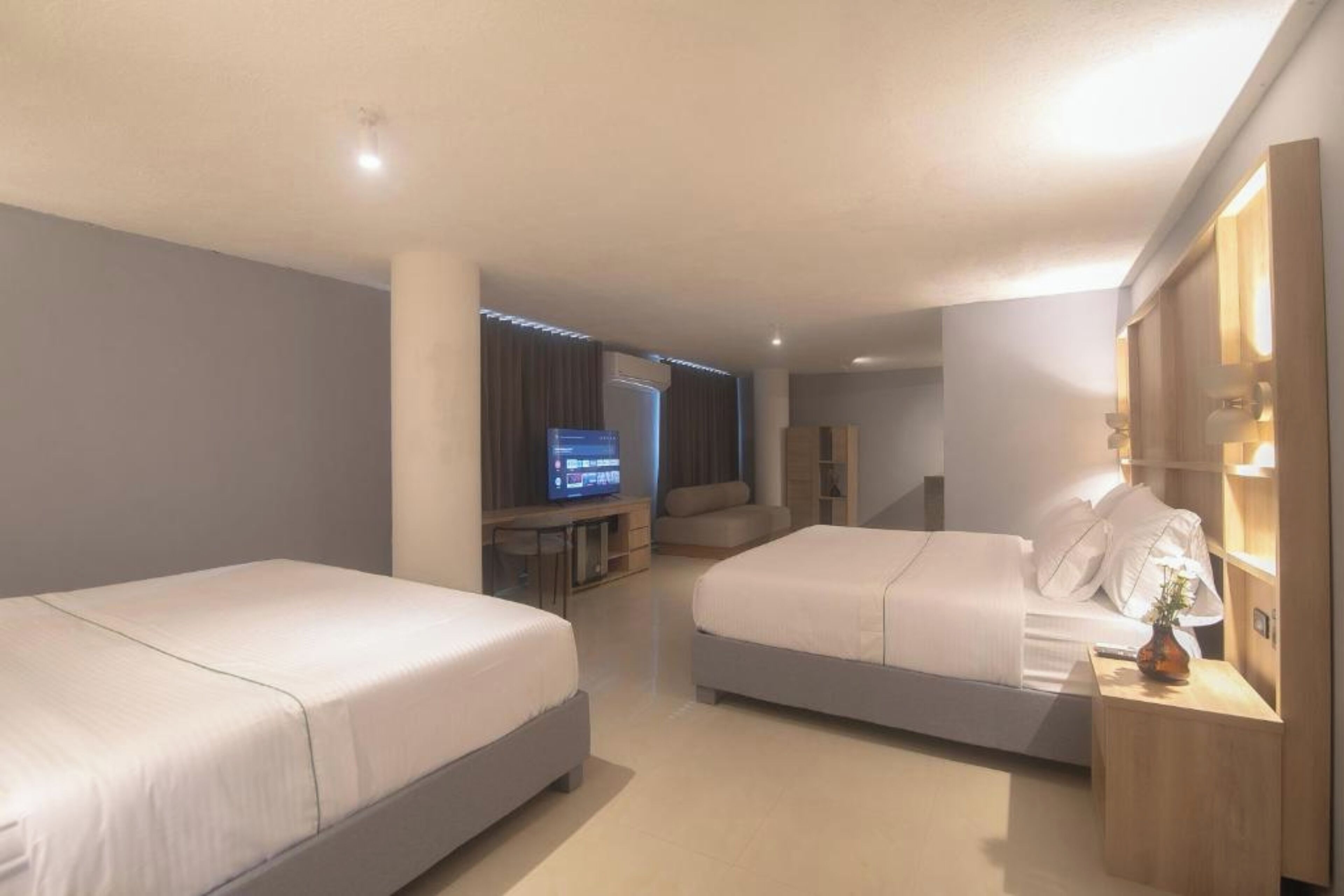 Una habitación de hotel con dos camas, televisión, escritorio y armario.