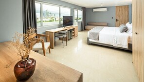 A modern hotel room with a bed, desk, and chair, a TV, and a view of the city. - Mood Matuna Hotel Cartagena (Cartagena)