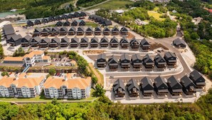 An aerial view of a resort with multiple lodge-style buildings arranged in a semi-circular pattern. There is a swimming pool and a parking area visible. - Nine Lakefront Homes (sleeping 223) in Rocky Shores w/n 500ft (HOLLISTER)