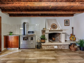 Cozy kitchen with stove, microwave, and sink, featuring a stone hearth and guitar.