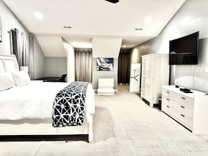 Habitación de hotel moderna con una cama grande, un escritorio, una silla, un armario y un televisor.