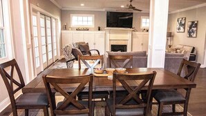 A dining area with a wooden table and chairs, a fireplace, and a television above it. - Modern comfort within walking distance from UKY, Kroger Field, & Chevy Chase. (Lexington)