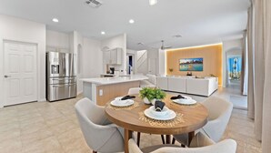 Una cocina moderna con isla integrada, electrodomésticos de acero inoxidable y un comedor con mesa y sillas de madera.