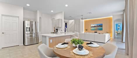 A modern kitchen with a built-in island, stainless steel appliances, and a dining area with a wooden table and chairs.