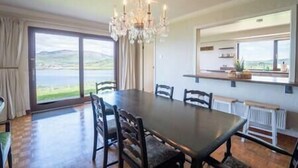 A dining area with a large table and chairs, a chandelier, and a view of the outdoors. - Dingle Bay Nest Burnham (Ventry)