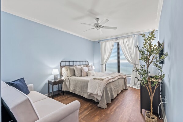 Un dormitorio con cama, mesita de noche, lámpara y ventilador de techo.