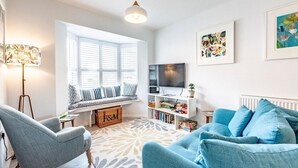 A modern living room with a large window, a sofa, a chair, a TV, and a bookshelf. - The Salty Dog, Aldeburgh (Suffolk)