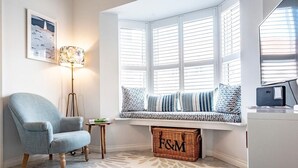 A cozy seating area with a bench, a lamp, and a wicker basket labeled "F&M". - The Salty Dog, Aldeburgh (Suffolk)