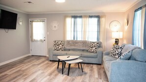 A living room with a grey sofa, a coffee table, and a TV mounted on the wall. - Cozy and Quiet Lafayette Home 2 (Lafayette Parish)