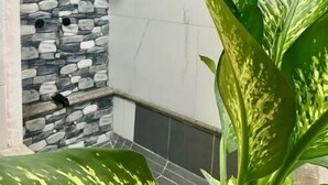 A corner of a room with a stone wall and a tiled floor. - Come In (Puerto Vallarta)
