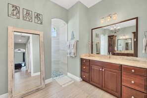 A bathroom with a large mirror, wooden cabinets, and a light green wall.